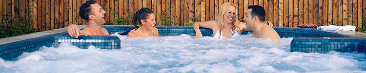 4 people laughing together in an outdoor jacuzzi. 